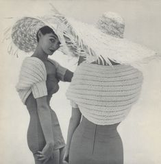 two women in dresses and hats standing next to each other