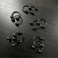 four pairs of metal balls and rings on a table with black wood grained surface