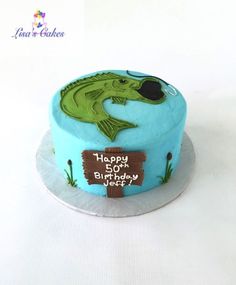 a blue birthday cake with a fish on it's side and happy birthday sign in the middle