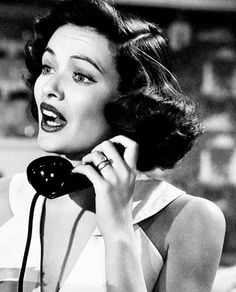 a woman talking on a telephone while wearing a dress