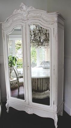 a white armoire with a mirror on it