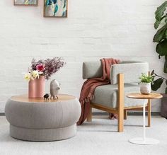 a living room filled with furniture and flowers on top of a coffee table in front of a white brick wall