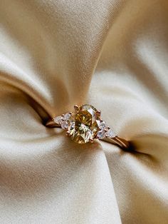 a diamond ring sitting on top of a white satin material covered in gold and diamonds