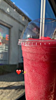 a red drink sitting on top of a table next to a car window with a straw sticking out of it