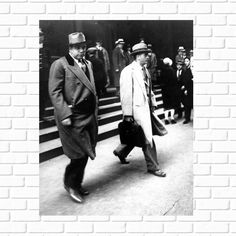 black and white photograph of two men walking down the street with people in the background