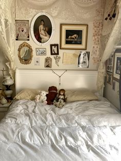 there is a bed with white sheets and pictures on the wall above it, along with two stuffed animals