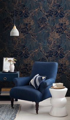 a blue chair sitting on top of a white floor next to a table and lamp