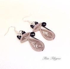 two silver and black earrings on a white surface