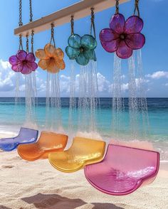 colorful glass flowers hanging from chains on the beach