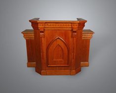 a wooden cabinet with an arched door on the front and side, against a gray background