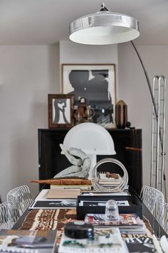 a dining room table with chairs and pictures on the wall in front of an art piece