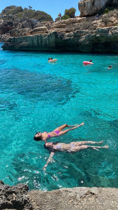 two people are swimming in the clear blue water