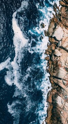 an aerial view of the ocean and rocks