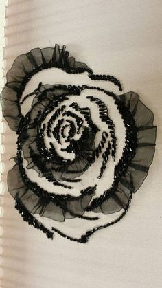 a black and white flower with beads on it's center is hanging from the wall