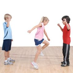 three children are standing on a wooden floor and one is holding his hand up to his ear