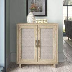 a white vase sitting on top of a wooden cabinet