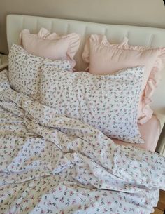 an unmade bed with pink and white sheets, pillows and blankets on top of it