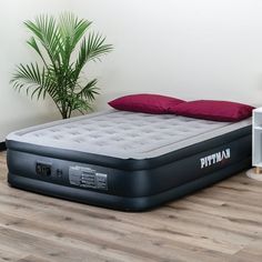 an inflatable mattress sitting on top of a wooden floor next to a plant