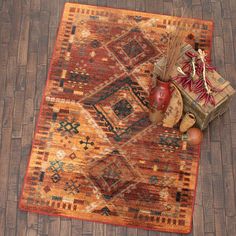 an orange rug with decorative items on it and a vase filled with dried flowers sitting on the floor