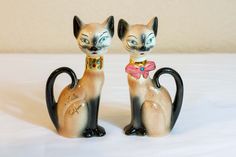 two ceramic figurines of cats with blue eyes