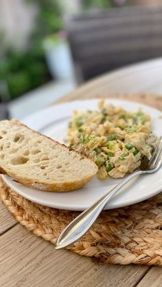 a white plate topped with bread and salad next to a fork on top of a table