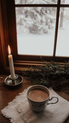 a cup of hot chocolate sitting on top of a table next to a candle