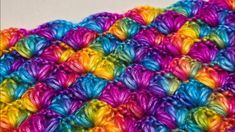 a multicolored crochet blanket is shown in close up on a white surface