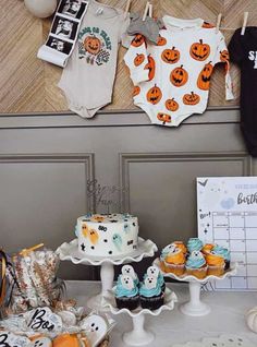 a baby shower party with cupcakes and halloween onesuits on the table