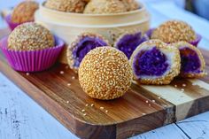 several different types of baked goods on a wooden cutting board next to a bowl with sesame seeds