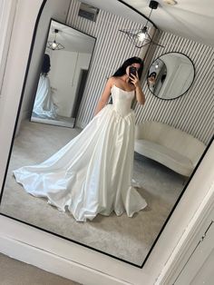 a woman in a wedding dress taking a selfie with her cell phone while standing in front of a mirror