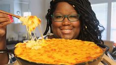 a woman holding up a large pizza with toppings in her hand while eating it