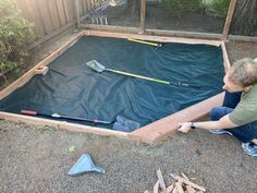 a man sitting on the ground next to a pool with shovels and rakes in it