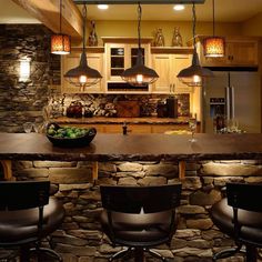 a kitchen that has some lights hanging from the ceiling and chairs in front of it