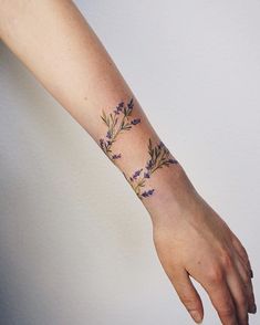 a woman's arm with flowers on it and the wrist is shown in purple