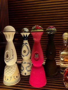 four different colored glass vases sitting on a shelf