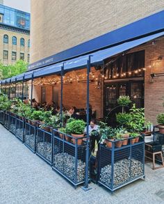 an outdoor restaurant with potted plants on the outside