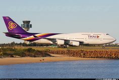 an airplane is parked on the runway by the water