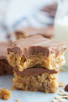 two pieces of chocolate peanut butter bars stacked on top of each other next to a glass of milk