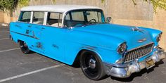 an old blue and white station wagon parked in a parking lot