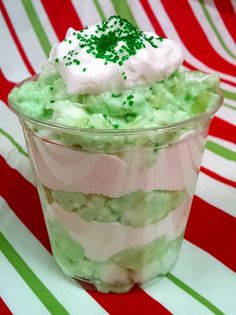 a green and white dessert in a plastic cup on a striped tablecloth with red and green stripes