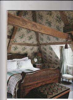 a bed in a bedroom with floral wallpaper on the walls and wooden beams above it