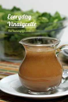 a glass pitcher filled with liquid sitting on top of a white plate next to a bowl of lettuce