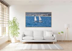 a living room with a white couch and two sailboats on the water in front of it