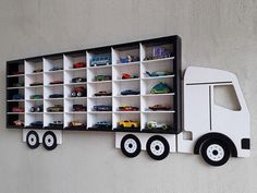 a toy truck is mounted on the wall next to a shelf with cars and trucks