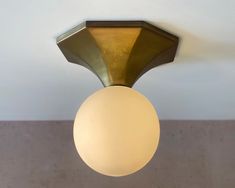 a ceiling light with a white ball hanging from it's center point in a room