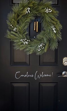 a black door with a green wreath on it and the words camelbles welcome written in white