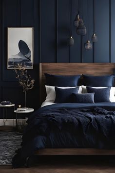 a bed with blue sheets and pillows in a room that has dark wood paneling