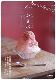 a bowl filled with pink ice cream on top of a wooden table next to a spoon