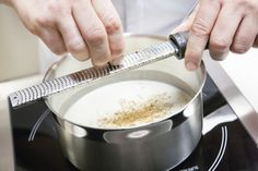 a person using a grater to stir food in a pot on top of the stove