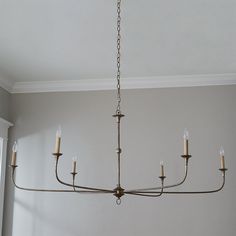 a chandelier hanging from the ceiling in a room with gray walls and white trim